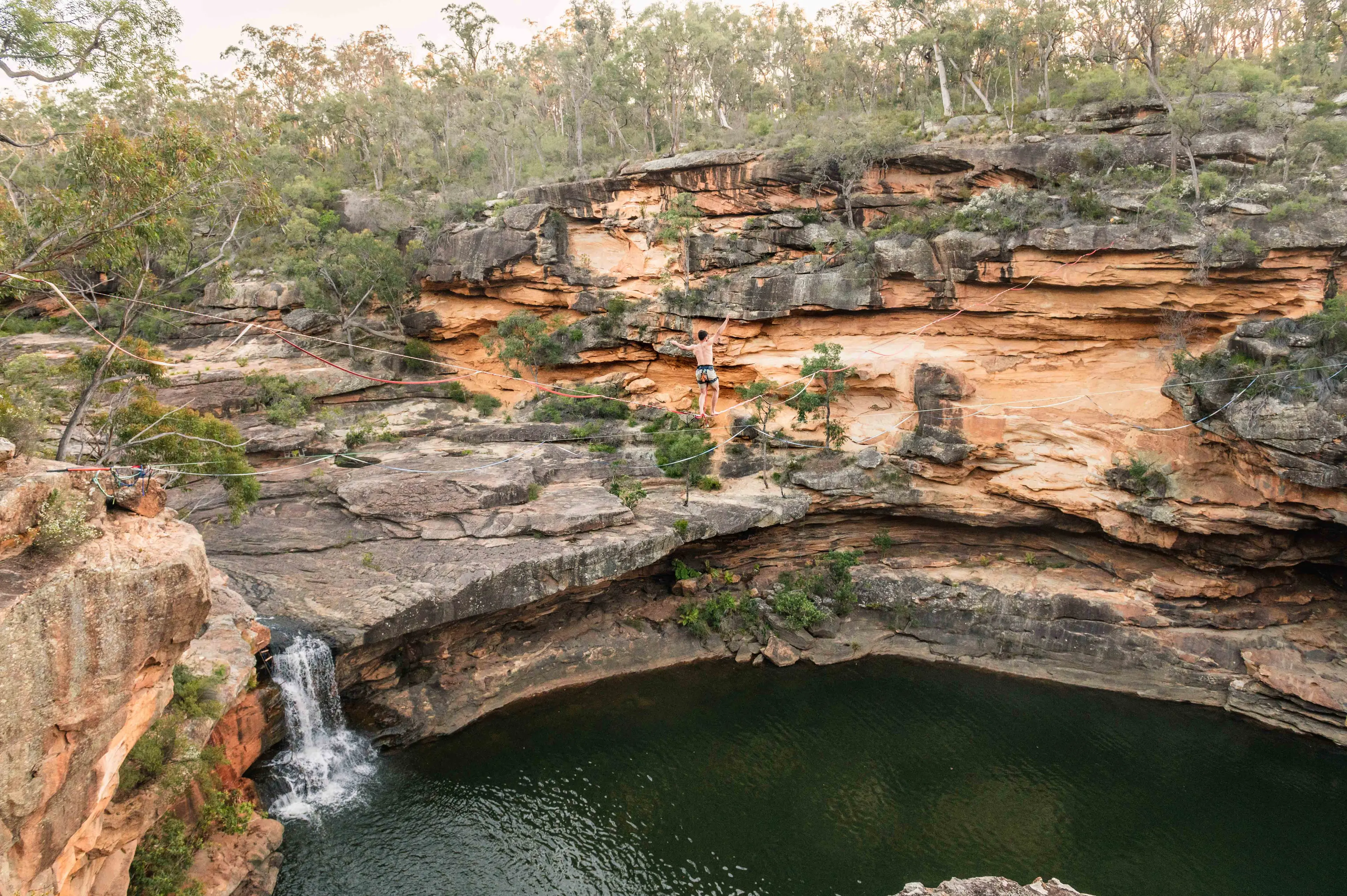 A highline (slackline) spot between the cliffs of Mermaid Pool, showing nearby waterhole and waterfall area.